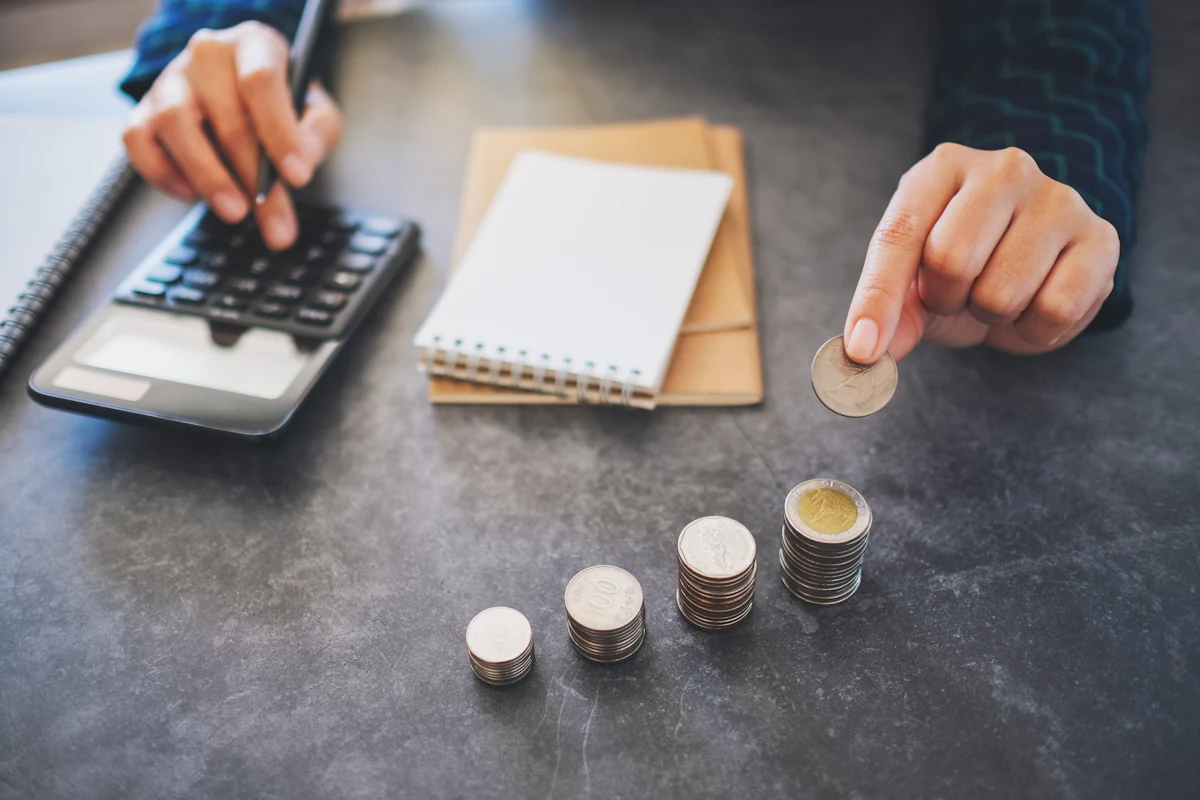 Une personne qui fait des calculs en alignant des pièces de monnaies devant lui