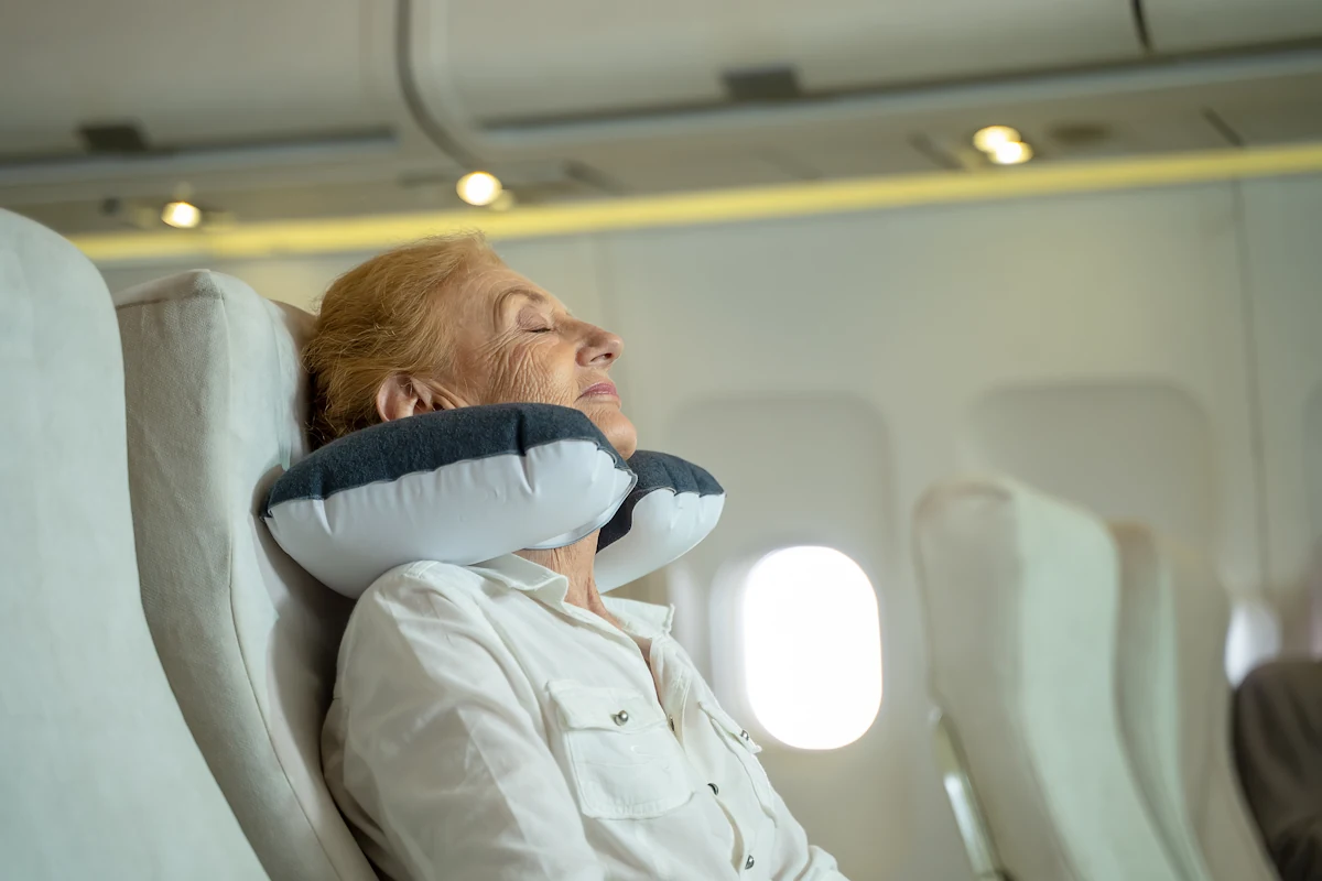 Une femme qui dort en avion avec un coussin cervical