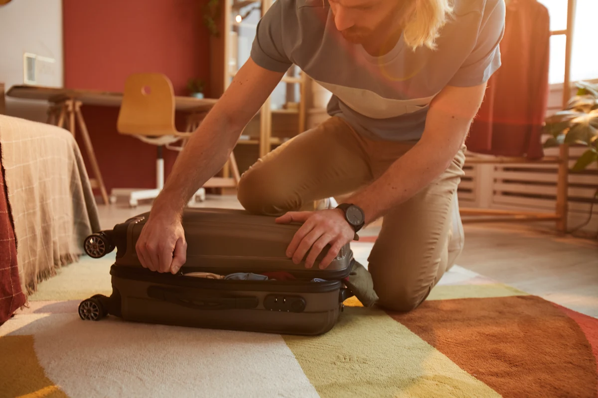 Un homme qui ferme une valise cabine