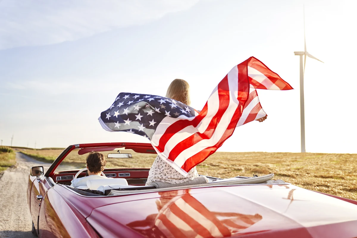 Un couple qui roule en voiture avec le drapeau des Etats-Unis