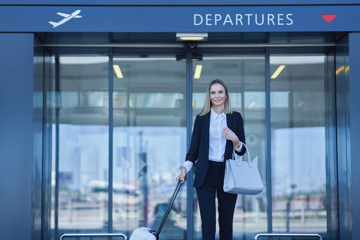 Une femme avec un valise devant la porte des départs d'un aéroport